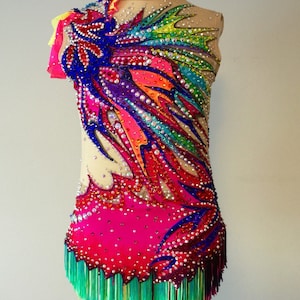 May include: A vibrant, custom-made rhythmic gymnastics leotard. The sleeveless garment features a nude mesh bodice, adorned with a colorful, abstract design of blue, pink, orange, and green. The design is embellished with rhinestones and a fringe hemline.