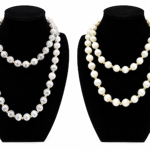 May include: Two long necklaces displayed on black stands. The left necklace features translucent, textured spherical beads with gold-tone spacers. The right necklace consists of solid, opaque white spherical beads separated by small gold-tone spacers.