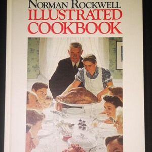 May include: The cover of "The Norman Rockwell Illustrated Cookbook" features a painting of a family gathered around a table for a Thanksgiving meal. A woman in a white apron is serving a roasted turkey to the family. The book cover is white with red and black text.