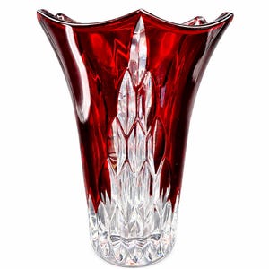 May include: A red glass vase with a unique, fluted design. The vase has a wide, scalloped rim and a clear, patterned base. The red color is concentrated at the top, fading into the clear, textured bottom. The vase is a decorative item.