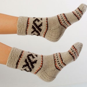 May include: A pair of knitted socks with a brown, orange, and beige pattern. The socks are made of a soft, warm material and are perfect for keeping your feet cozy in the winter.