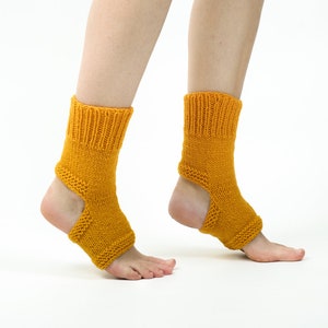 May include: A pair of yellow knitted ankle socks with a cut-out at the heel. The socks are worn on a person's feet.
