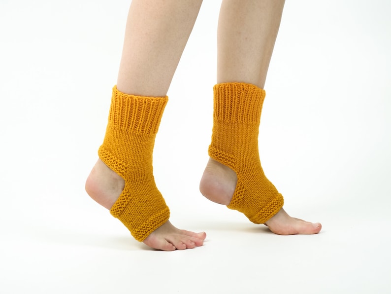 May include: A pair of yellow knitted ankle socks with a cut-out at the heel. The socks are worn on a person's feet.