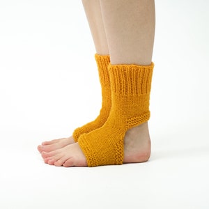 May include: A pair of yellow knitted ankle socks with an opening at the heel. The socks are worn on a person's feet.
