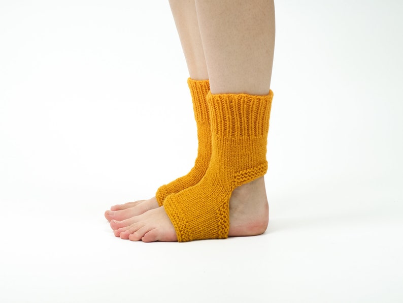 May include: A pair of yellow knitted ankle socks with an opening at the heel. The socks are worn on a person's feet.