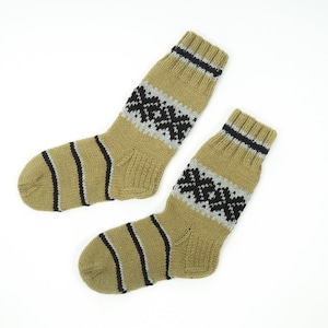 May include: A pair of beige wool socks with black and grey geometric patterns. The socks are knitted and have a ribbed texture.