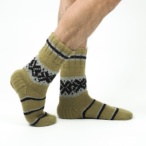 May include: A pair of brown and black patterned socks with a grey stripe. The socks are made of a soft, knitted material.