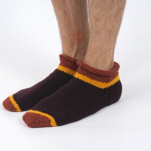 Könnte beinhalten: Ein Paar braune Knöchelsocken mit orangefarbenen und gelben Streifen am oberen Rand.