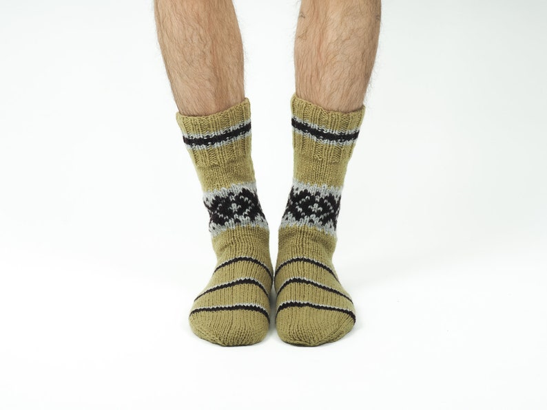 May include: A pair of beige socks with black and grey stripes and a geometric pattern. The socks are made of a soft, knitted fabric.