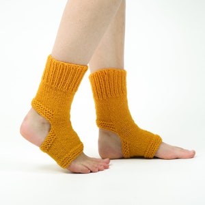 May include: A pair of yellow knitted ankle socks with an opening at the heel. The socks are worn on a person's feet.