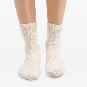 May include: A pair of white knitted socks with a ribbed cuff.