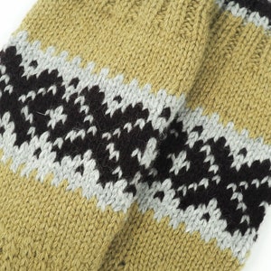 May include: Close-up of a knitted fabric with a striped pattern in shades of brown, black, and gray. The fabric has a textured, hand-knitted look.