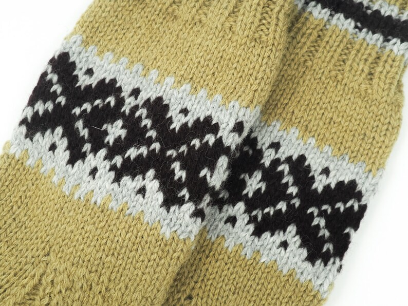 May include: Close-up of a knitted fabric with a striped pattern in shades of brown, black, and gray. The fabric has a textured, hand-knitted look.