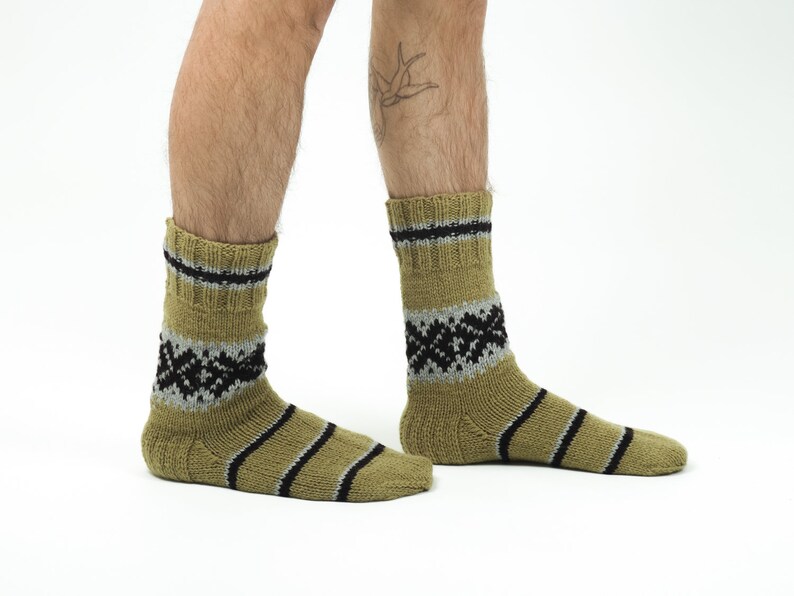 May include: A pair of olive green socks with black and gray stripes and a geometric pattern. The socks are made of a soft, knitted fabric.
