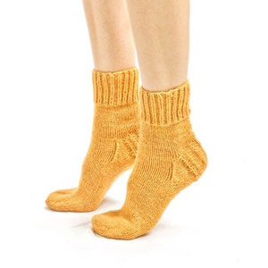 May include: A pair of yellow knitted ankle socks. The socks are made of a soft, comfortable material and have a ribbed texture.