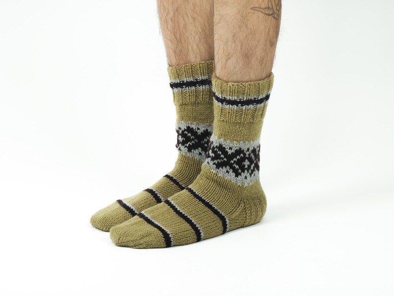May include: A pair of olive green socks with black and gray stripes and a geometric pattern. The socks are made of a soft, knitted fabric.
