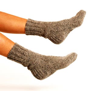 May include: Two pairs of brown wool socks, one on each foot, with the toes of the socks pointing up.