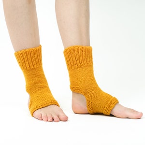 May include: A pair of yellow knitted ankle socks with an open heel design. The socks are made of a soft, comfortable material and are perfect for yoga or other activities.