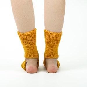 May include: A pair of yellow knitted socks with a ribbed pattern. The socks are pulled up to the ankles and are worn on a person's feet.