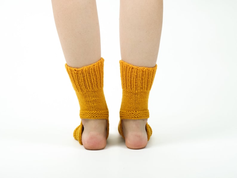 May include: A pair of yellow knitted socks with a ribbed pattern. The socks are pulled up to the ankles and are worn on a person's feet.