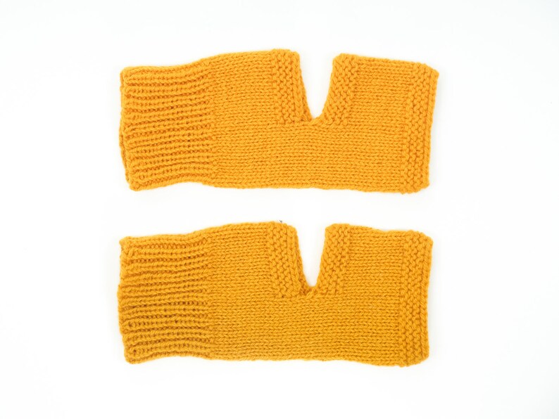 May include: A pair of yellow knitted arm warmers with a hole for the thumb.
