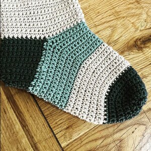 May include: A crocheted stocking with stripes of teal, beige, and dark green.