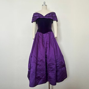 May include: A purple off-the-shoulder gown with a velvet bodice and a flowing satin skirt.