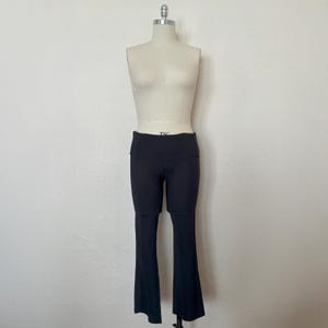 May include: Black yoga pants with a flared leg design. The pants have a high waistband and are displayed on a mannequin. The pants are made of a stretchy material and are designed for comfort and flexibility. The pants are a solid color and are suitable for various activities.