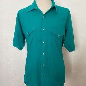 Front view of 1980s vintage teal pearl snap short sleeve western shirt, by Sheplers, size medium to large.