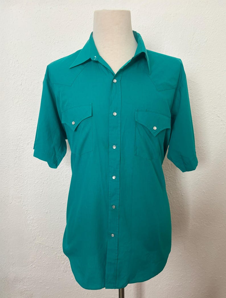 Front view of 1980s vintage teal pearl snap short sleeve western shirt, by Sheplers, size medium to large.