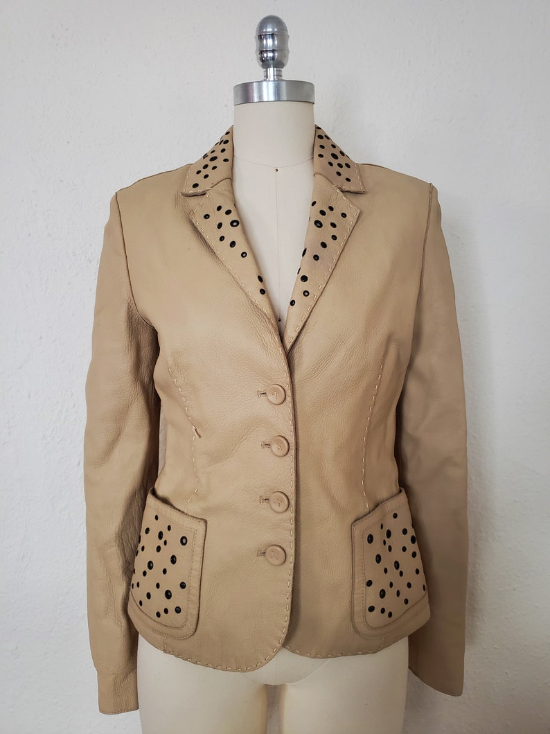 Front view of 1990s topstitched metal eyelet and stud embellished buff leather blazer by Donald Pliner, extra small to small.