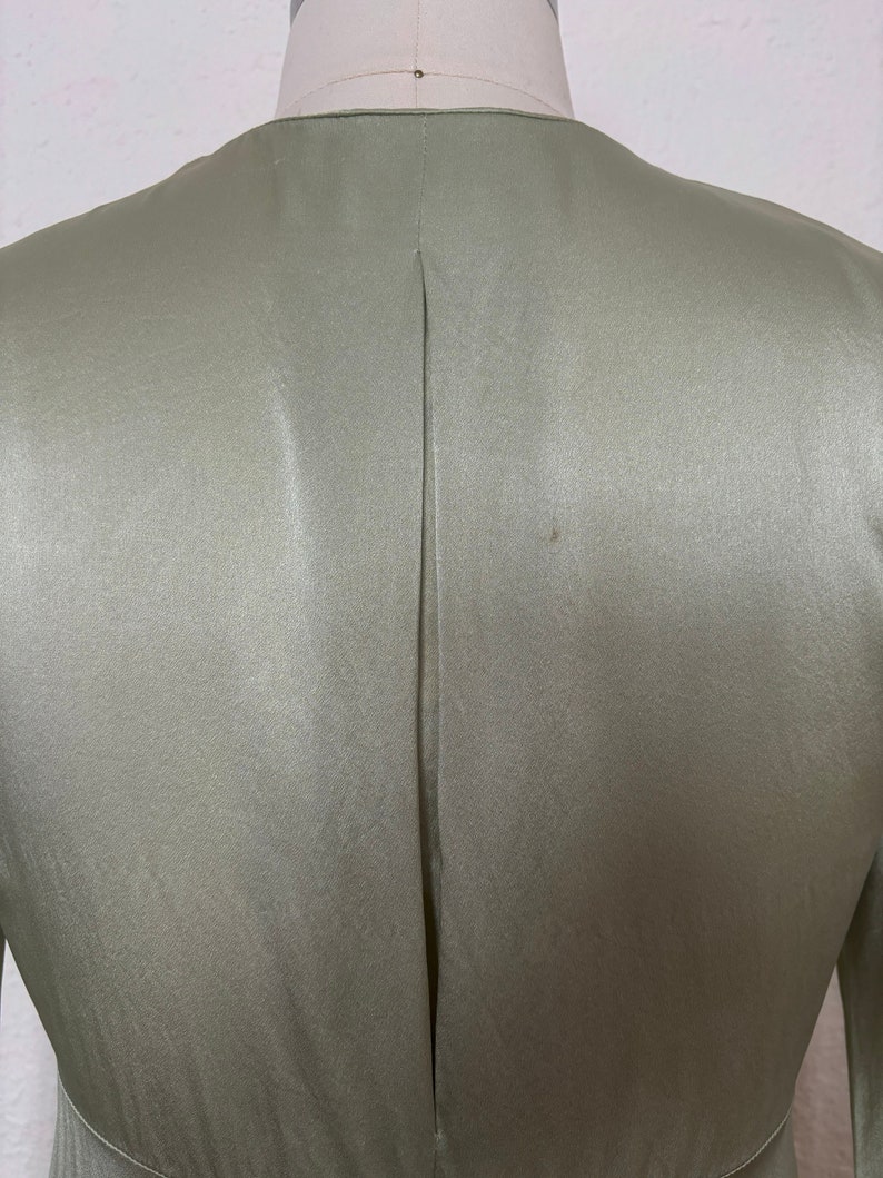 Detail view of 2000s y2k vintage new with tags sage green silk charmeuse robe by Patricia Fieldwalker, size medium to large. Showing the pleat at the center back.