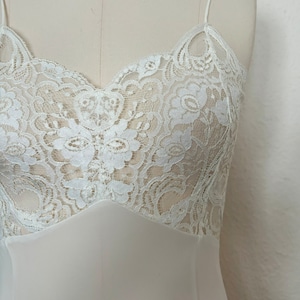 Detail view of 2000s y2k vintage new with tags white georgette and lace sheer floor length nightgown with train by Jane Woolrich, size extra small to small. Showing the sheer white floral lace bust.