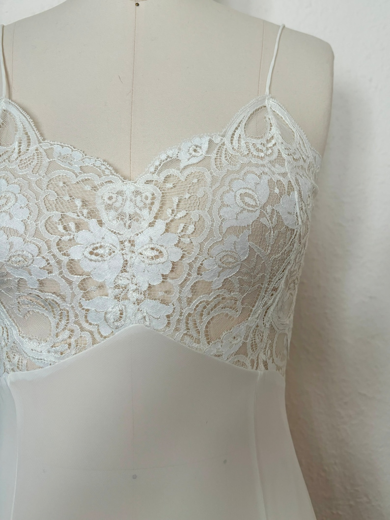 Detail view of 2000s y2k vintage new with tags white georgette and lace sheer floor length nightgown with train by Jane Woolrich, size extra small to small. Showing the sheer white floral lace bust.