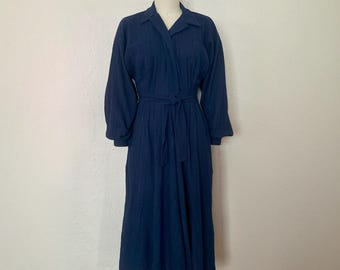 May include: A navy blue long-sleeved dress with a wrap style bodice and a tie belt. The dress has a slightly puffed sleeve and a midi length.