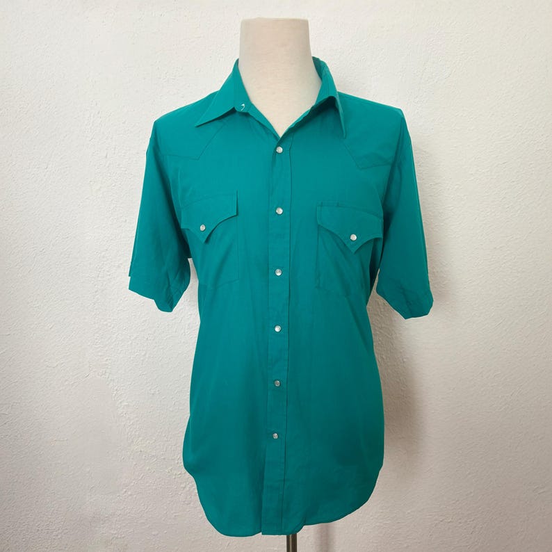 Front view of 1980s vintage teal pearl snap short sleeve western shirt, by Sheplers, size medium to large.