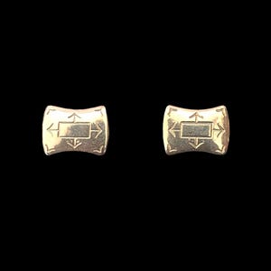 May include: A pair of gold-toned cufflinks with a geometric design. Each cufflink features a square with arrows pointing in all four directions.