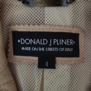 Detail view of 1990s topstitched metal eyelet and stud embellished buff leather blazer by Donald Pliner, extra small to small, showing the tag and label.