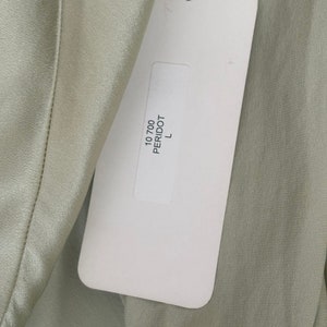 Interior detail view of 2000s y2k vintage new with tags sage green silk charmeuse robe by Patricia Fieldwalker, size medium to large. Showing the paper store tag with the color peridot and size L.