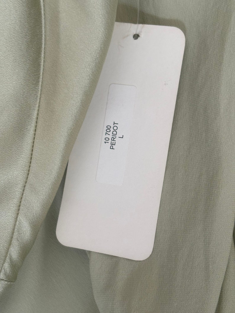 Interior detail view of 2000s y2k vintage new with tags sage green silk charmeuse robe by Patricia Fieldwalker, size medium to large. Showing the paper store tag with the color peridot and size L.