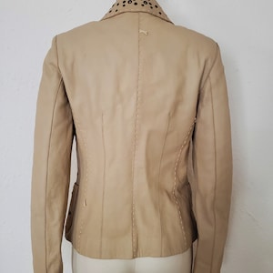 Back view of 1990s topstitched metal eyelet and stud embellished buff leather blazer by Donald Pliner, extra small to small
