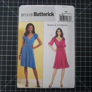May include: A Butterick sewing pattern featuring two dress designs by Maggy London. The pattern shows illustrations of a blue and a pink dress, both with V-necklines and gathered skirts. The pattern number is B5318, with sizes 8-10-12-14.