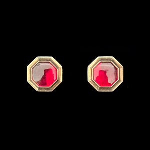 May include: A pair of gold-toned earrings with red octagonal gemstones.
