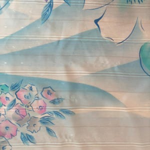 Detail view of 1980s vintage large pink, blue, and white floral print square sheer striped polyester scarf. Showing a close-up of the blue and pink floral print and the snags in the polyester.