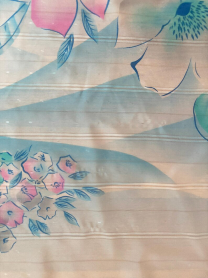 Detail view of 1980s vintage large pink, blue, and white floral print square sheer striped polyester scarf. Showing a close-up of the blue and pink floral print and the snags in the polyester.