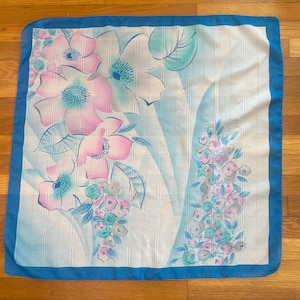 Horizontal front view of 1980s vintage large pink, blue, and white floral print square sheer striped polyester scarf.