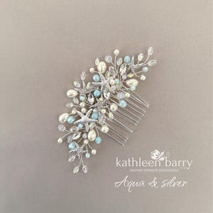 May include: A silver hair comb featuring a cluster of starfish, white pearls, and light blue beads on thin wire branches. The text kathleen barry bespoke occasion accessories and Aqua & silver is printed in white in the bottom right corner.