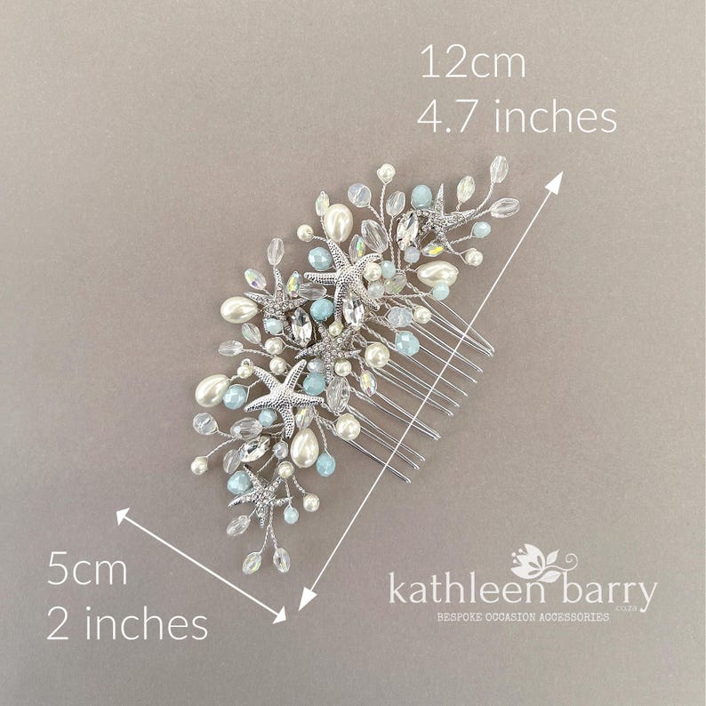 May include: A silver hair comb featuring starfish, white pearls, and light blue beads on wire branches. The accessory measures 12 cm by 5 cm, or 4.7 inches by 2 inches. The text "kathleen barry" is printed in the bottom right corner.