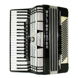 May include: A black and silver Weltmeister Amigo accordion with white and black keys. The accordion has a rectangular shape with a keyboard on the left side and a button panel on the right. The text "WELTMEISTER" is printed vertically.