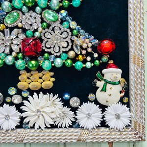 May include: A framed Christmas tree made of various vintage jewellery and ornaments, including rhinestones, beads, and a snowman figurine.